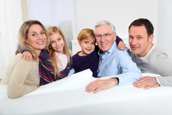 Retrato de família feliz sentado no sofá em casa — Fotografia de Stock