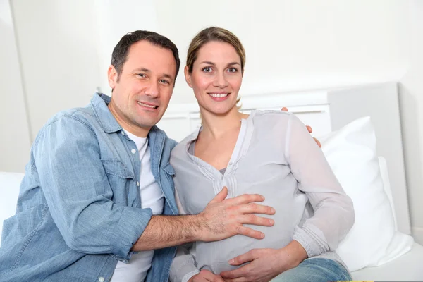 Future parents sitting in sofa at home — Stock Photo, Image
