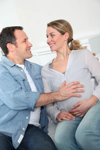 Future parents sitting in sofa at home — Stock Photo, Image