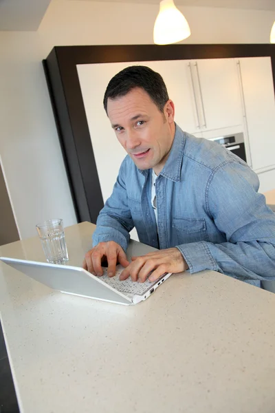 Seorang pria menggunakan komputer laptop di dapur — Stok Foto