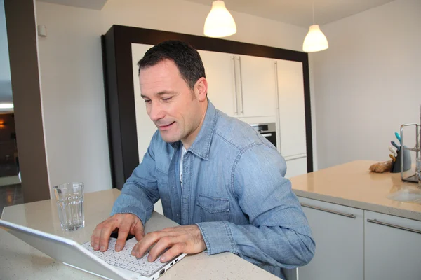 Άνθρωπος χρησιμοποιώντας φορητό υπολογιστή στην κουζίνα — Φωτογραφία Αρχείου