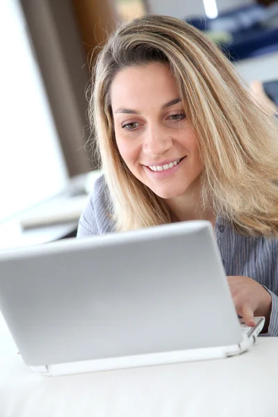 Donna sorridente connessa su internet a casa — Foto Stock