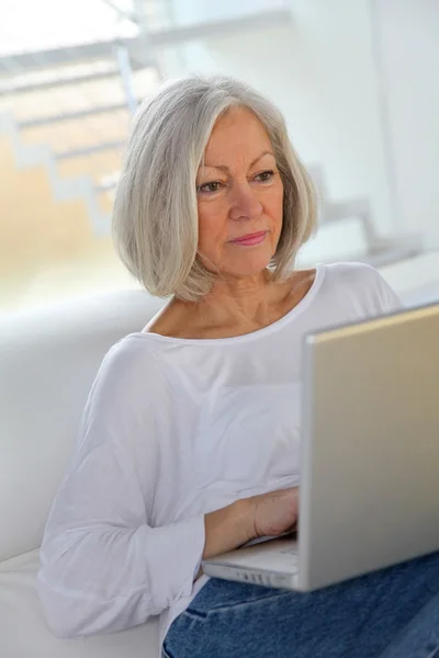 年配の女性が自宅でインターネット上でサーフィン — ストック写真