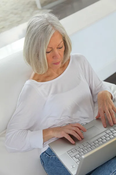 Starszy kobieta surfing na internet w domu — Zdjęcie stockowe