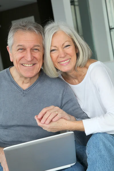 Senior couple sitting in sofa with laptop computer — Stock Photo, Image