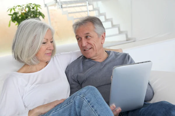 Старша пара сидить у дивані з електронним планшетом — стокове фото