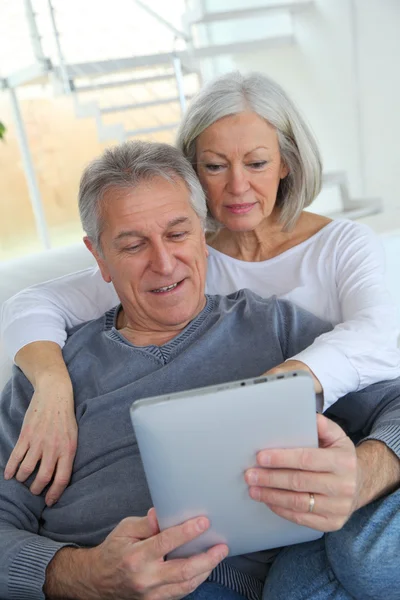電子タブレットでソファに座っている年配のカップル — ストック写真
