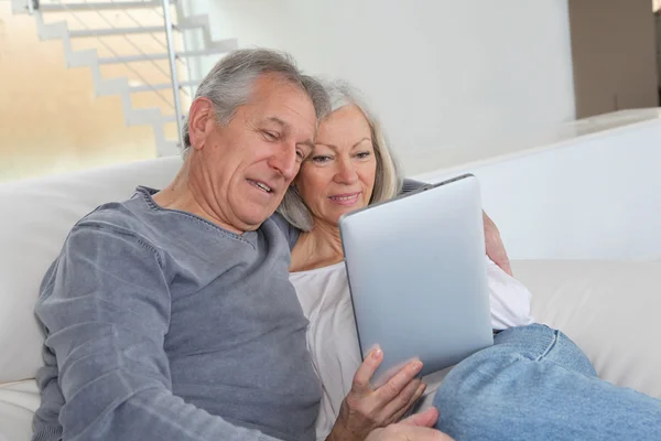 Старша пара сидить у дивані з електронним планшетом — стокове фото
