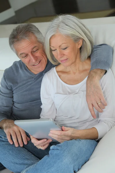 電子タブレットでソファに座っている年配のカップル — ストック写真
