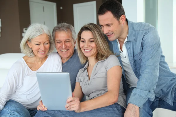 Ül a kanapén elektronikus tabletta boldog családi portré — Stock Fotó