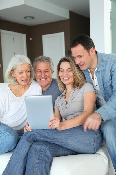 Retrato de familia feliz sentada en sofá con tableta electrónica —  Fotos de Stock