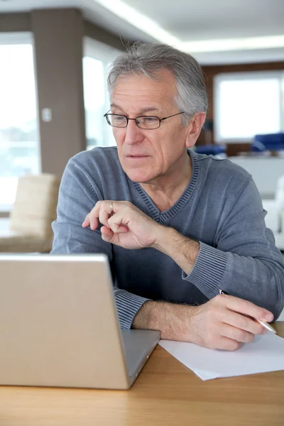 Senior man at home in front of laptop computer — Stock Photo, Image