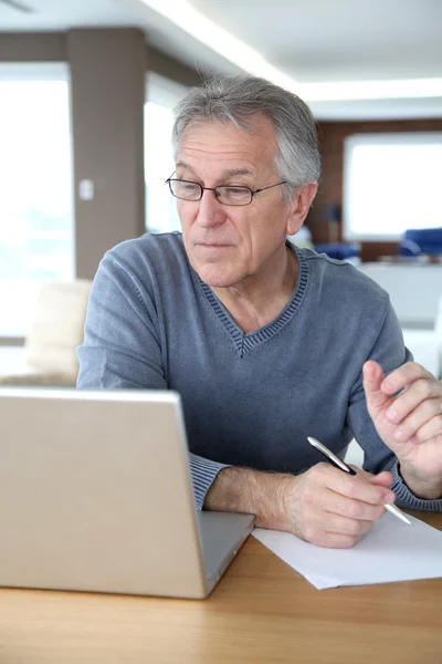 Starší muž doma před přenosný počítač — Stock fotografie