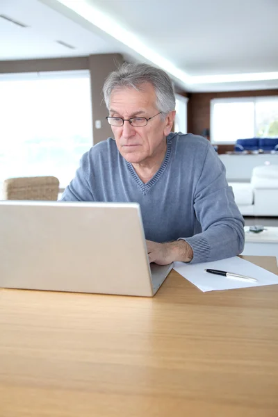 Uomo anziano a casa davanti al computer portatile — Foto Stock