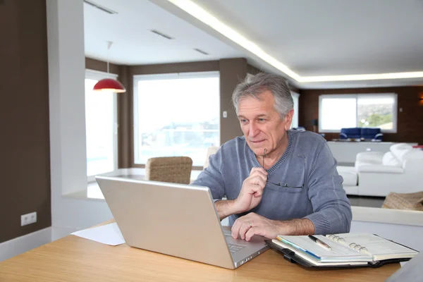 Hombre mayor en casa delante de la computadora portátil — Foto de Stock