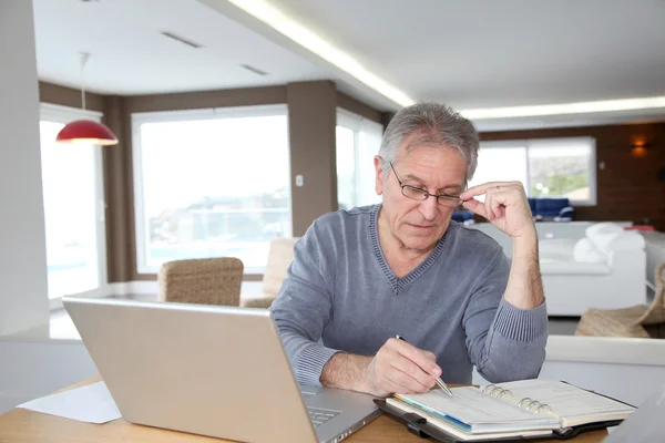 Hombre mayor en casa delante de la computadora portátil — Foto de Stock