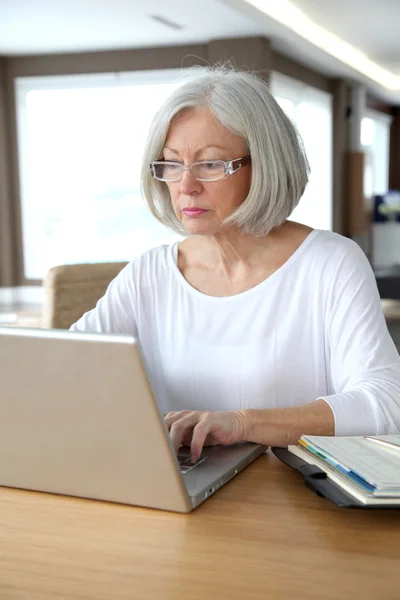 Ανώτερος γυναίκα στο σπίτι μπροστά από το φορητό υπολογιστή — Φωτογραφία Αρχείου