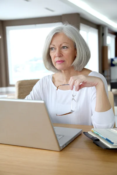 Mujer mayor en casa delante de la computadora portátil — Foto de Stock