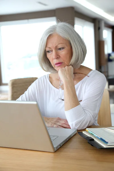 Üst düzey kadın evde dizüstü bilgisayar önünde — Stok fotoğraf