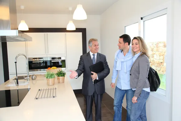 Real estate agent showing modern house to couple — Stock Photo, Image
