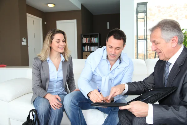 Ehepaar mit Immobilienmakler unterschreibt Vertrag über Eigenheiminvestitionen — Stockfoto