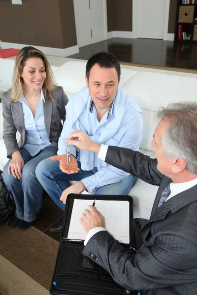 Real-estate agent giving house keys to young owners — Stock Photo, Image