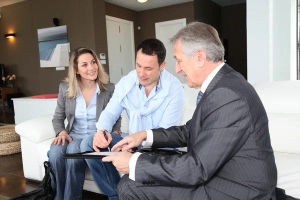 Ehepaar mit Immobilienmakler unterschreibt Vertrag über Eigenheiminvestitionen — Stockfoto