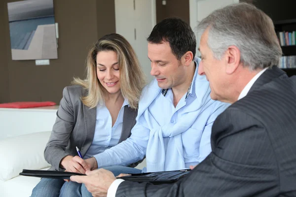 Couple avec un agent immobilier signant un contrat d'investissement immobilier — Photo