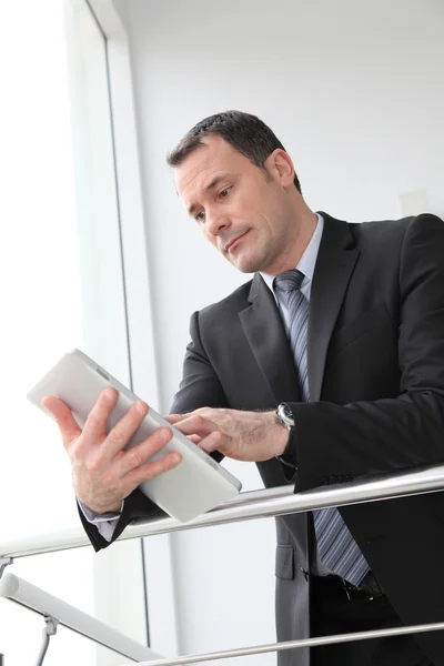Бизнесмен, стоящий в зале с электронным планшетом — стоковое фото