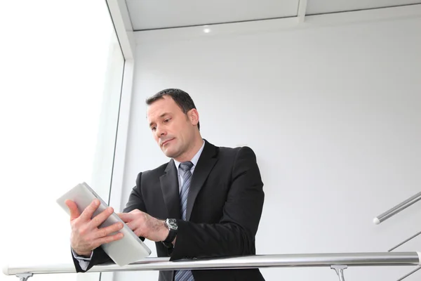 Empresário de pé no hall com tablet eletrônico — Fotografia de Stock