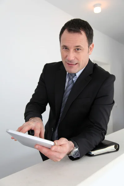 Businessman standing in hall with electronic tablet — Stock Photo, Image