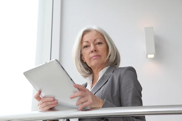 Senior zakenvrouw met behulp van elektronische tablet in hal — Stockfoto