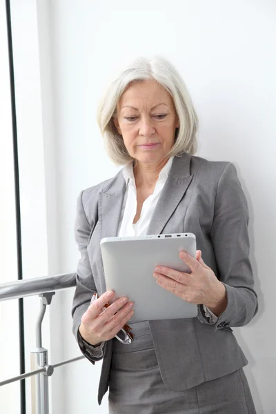 Mujer de negocios senior usando tableta electrónica en la sala — Foto de Stock