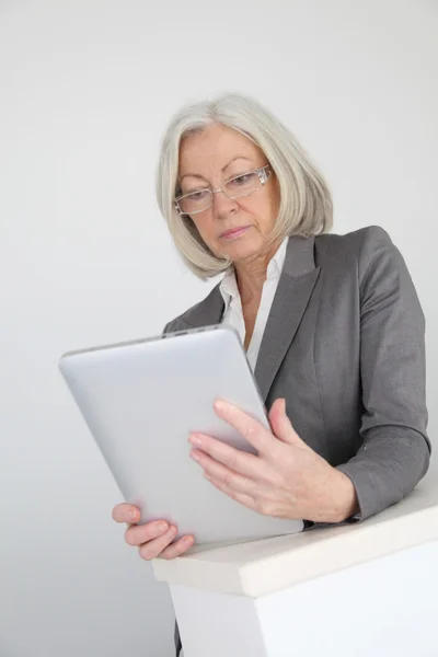 Donna d'affari anziana che utilizza tablet elettronico in sala — Foto Stock