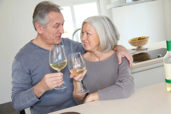 Старшая пара пьет вино на домашней кухне — стоковое фото