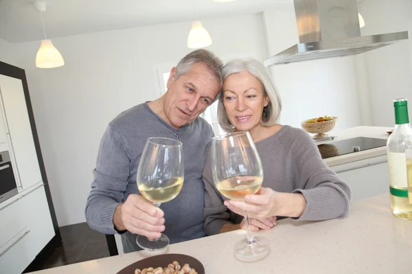 Starszy kilka picia wina w domu kuchnia — Zdjęcie stockowe