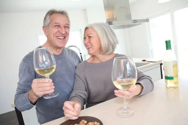 Pareja mayor bebiendo vino en casa cocina — Foto de Stock