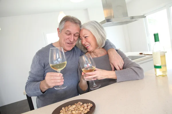 Starší pár, pití vína v domácí kuchyni — Stock fotografie