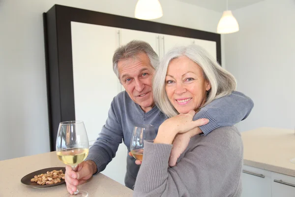 Старша пара п'є вино на домашній кухні — стокове фото