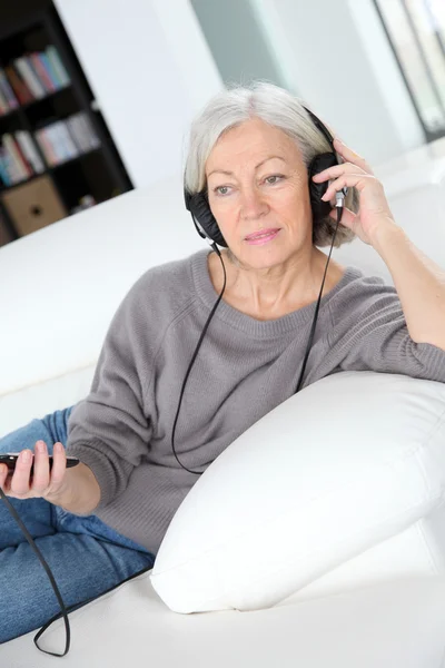 Senior vrouw luisteren naar muziek met een hoofdtelefoon — Stockfoto