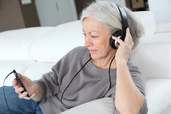 Wanita senior mendengarkan musik dengan headphone — Stok Foto