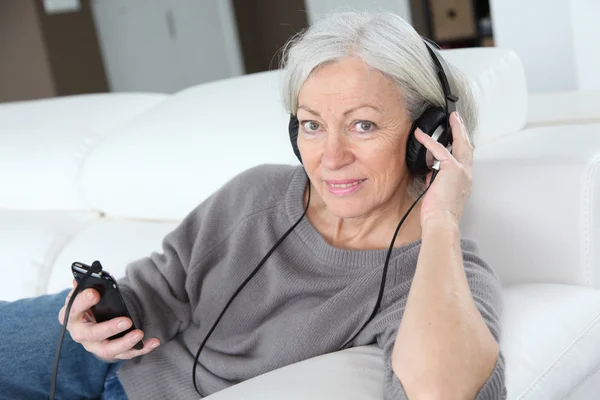 Senior vrouw luisteren naar muziek met een hoofdtelefoon — Stockfoto