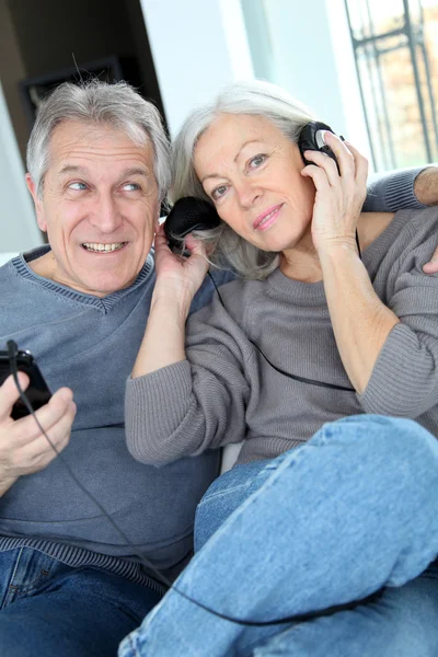 Coppia anziana che ascolta musica con le cuffie — Foto Stock
