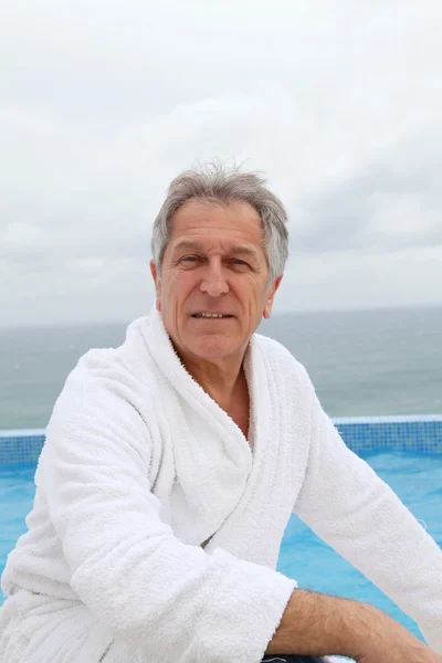 Senior man zit bij zwembad — Stockfoto