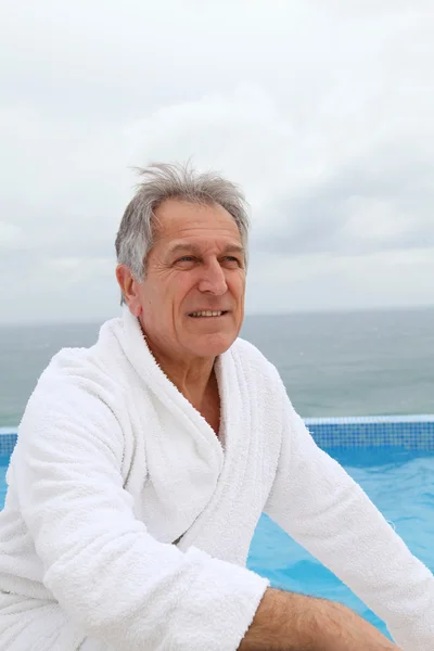 Starší muž, sedící u bazénu — Stock fotografie