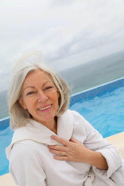 Senior mulher sentado à beira da piscina — Fotografia de Stock