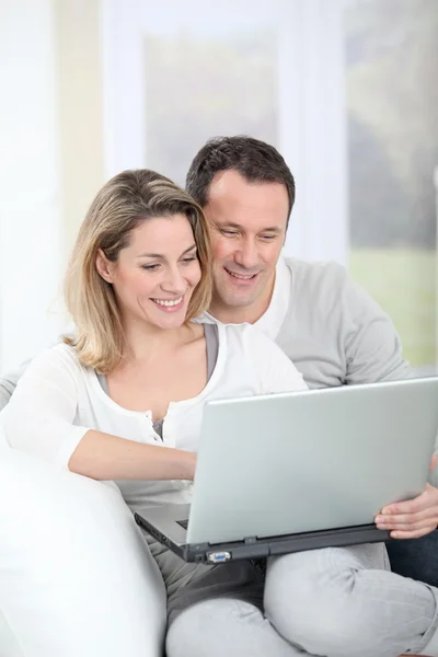Couple sitting in sofa with laptop computer Royalty Free Stock Images