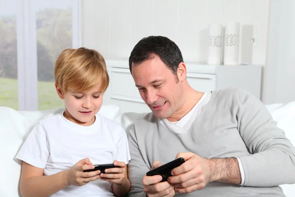 Батько і син грають у відеогру вдома Ліцензійні Стокові Фото