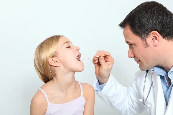 Pediatrician checking little girl throat Stock Picture