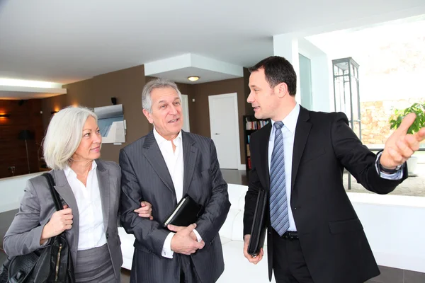 Senior couple visiting modern house with real-estate agent Stock Image
